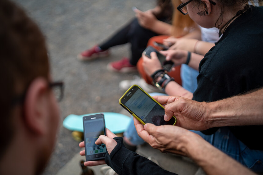 Man schaut von oben mehreren Personen über die Schulter, während alle Smartphones in den Händen halten.